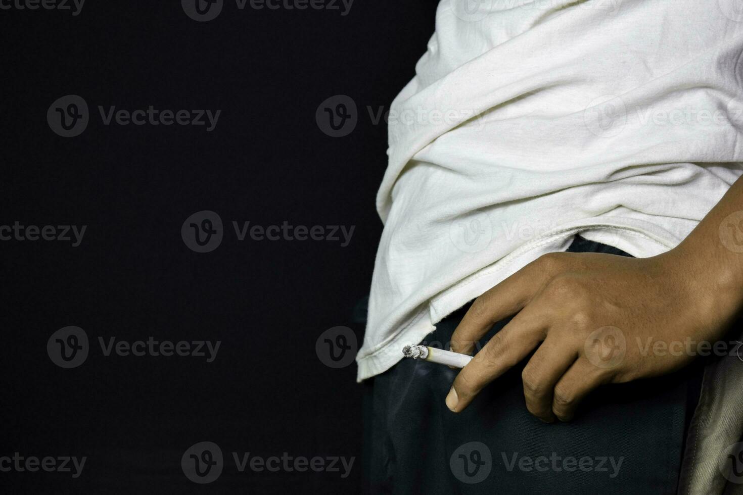 mano de asiático hombre participación cigarrillos con negro antecedentes. de fumar cigarrillos concepto foto