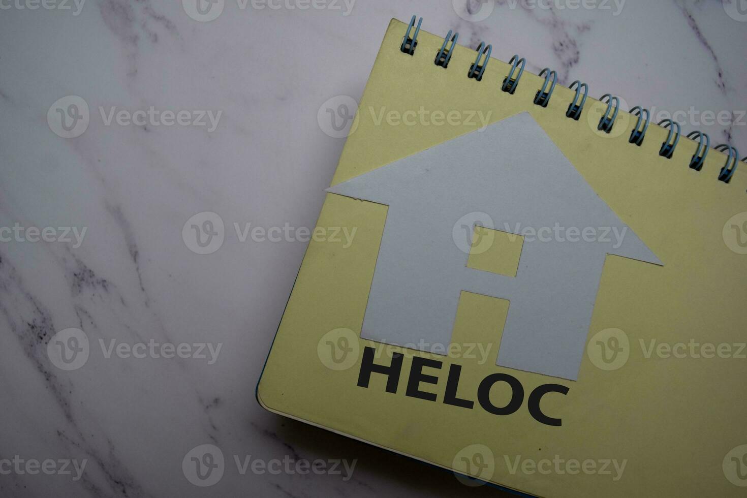 HELOC write on sticky note and house made from paper isolated on Office Desk. photo