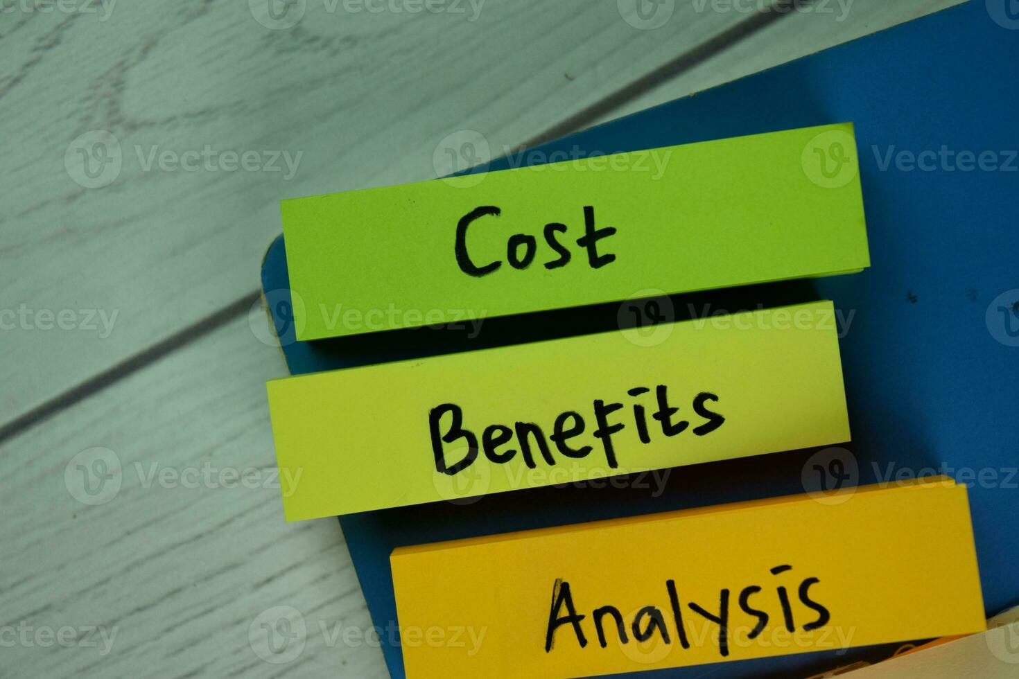 Cost Benefits Analysis write on sticky notes isolated on Wooden Table. photo
