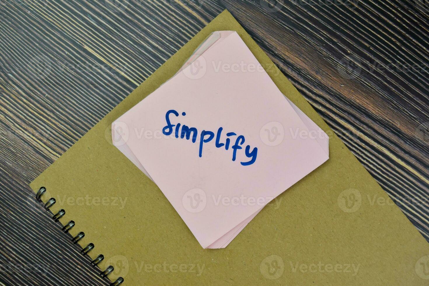 Concept of Simplify Reminder write on sticky notes isolated on Wooden Table. photo