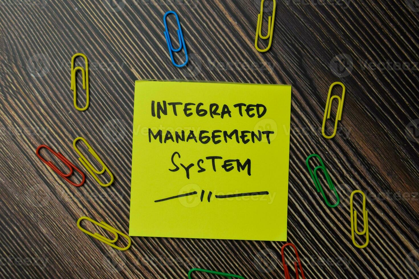 integrated management system write on sticky notes isolated on office desk. photo