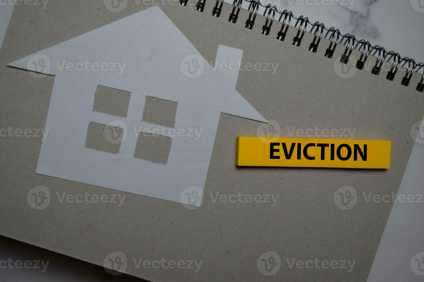 Eviction write on sticky note and house made from paper isolated on Office Desk. photo