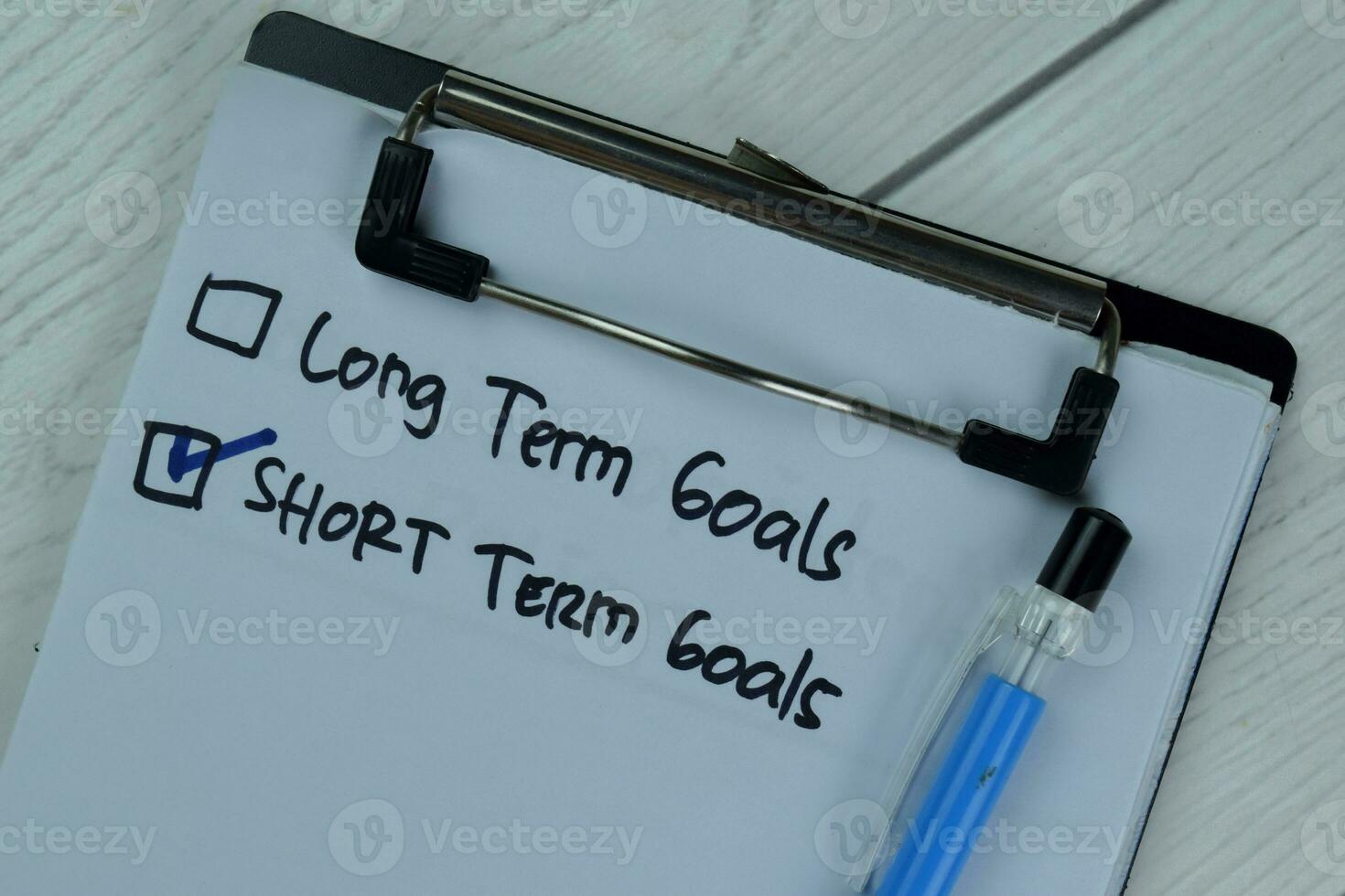 Concept of Short Term Goals write on a paperwork isolated on Wooden Table. photo