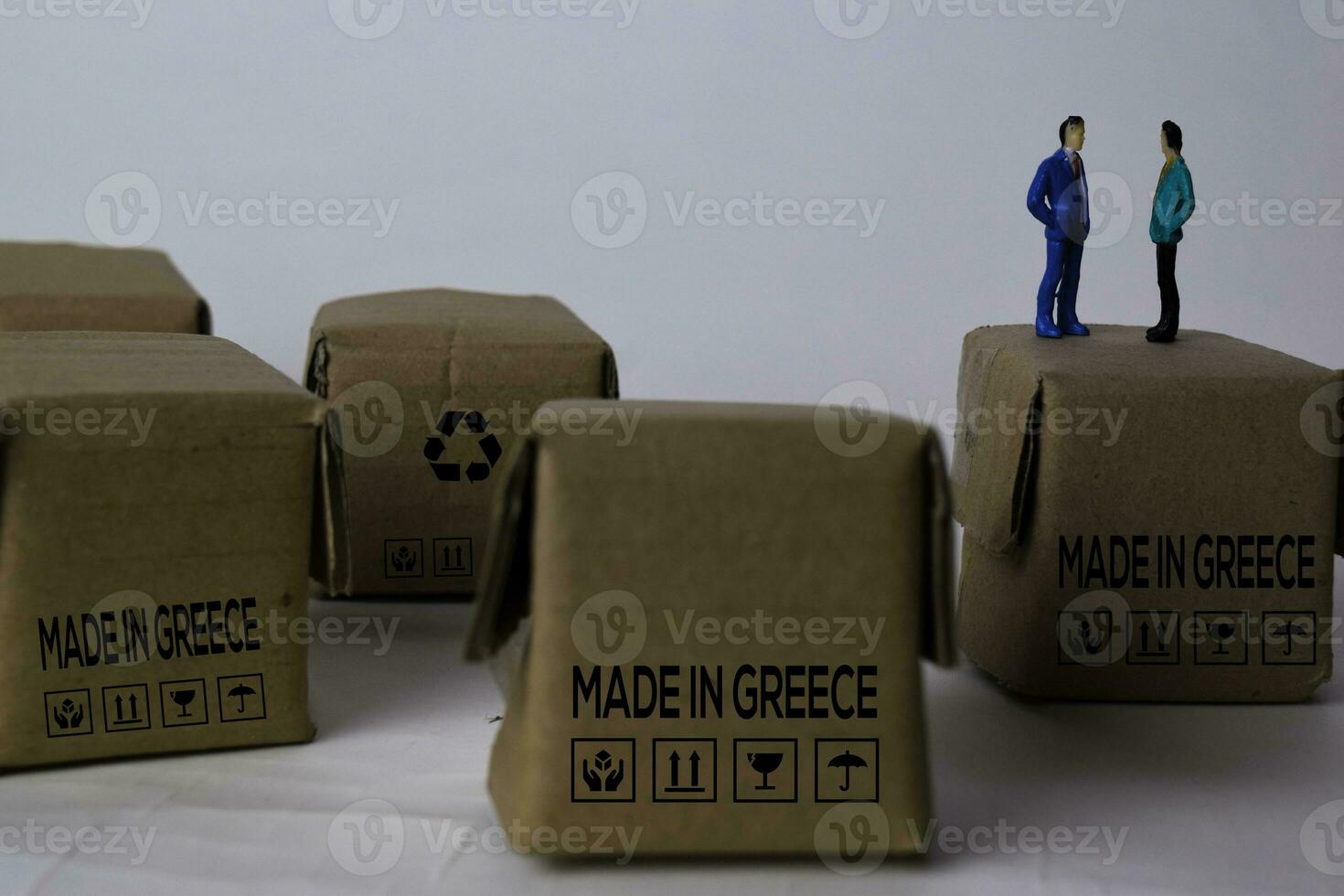 miniatura empresario hablando en cajas con texto hecho en Grecia aislado blanco fundamento foto