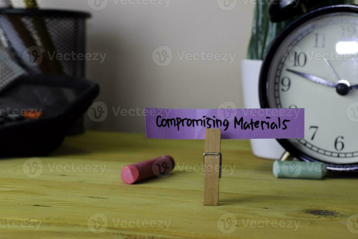 Compromising Materials. Handwriting on sticky notes in clothes pegs on wooden office desk photo