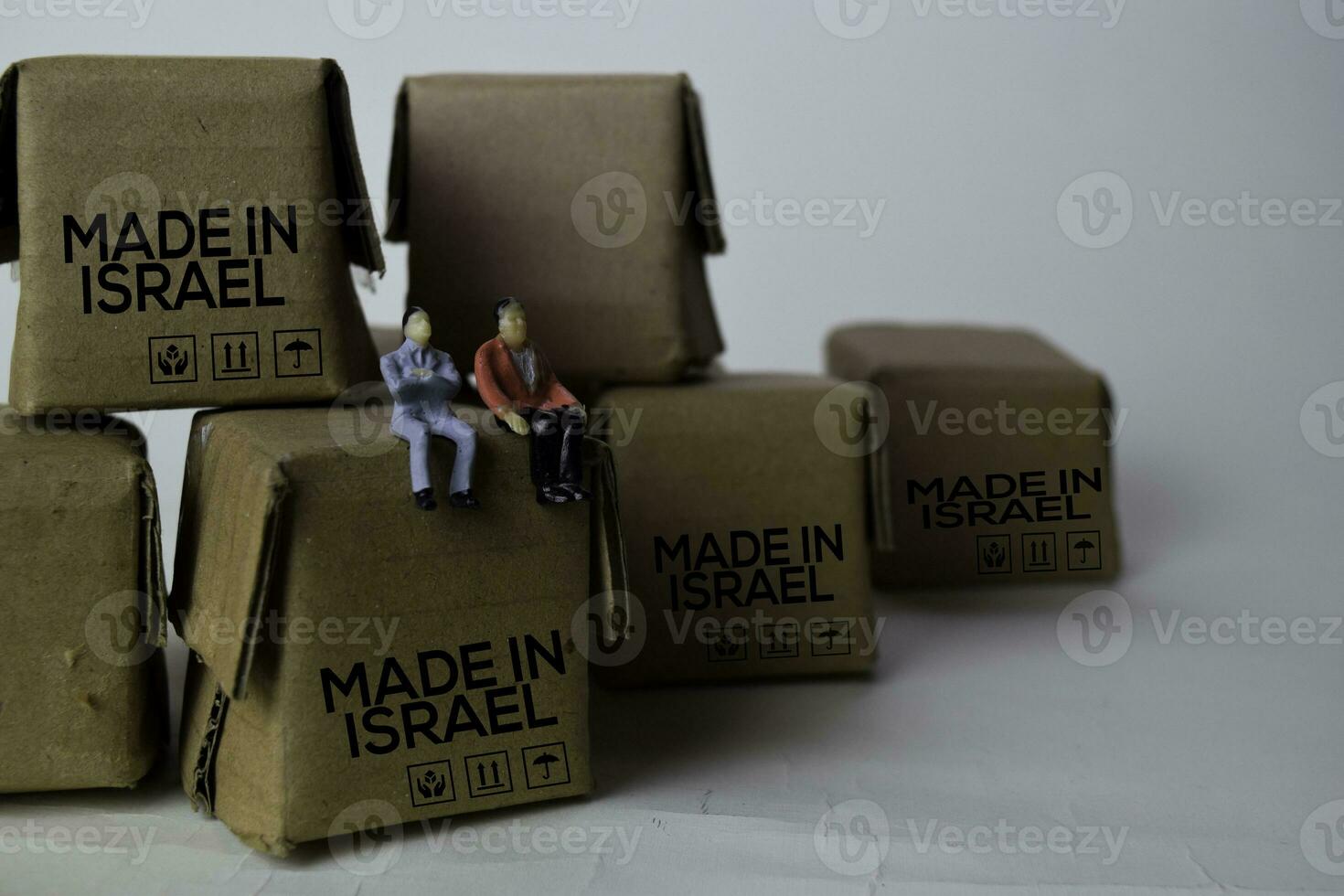 miniatura empresario sentado en cajas con texto hecho en Israel aislado blanco fundamento foto