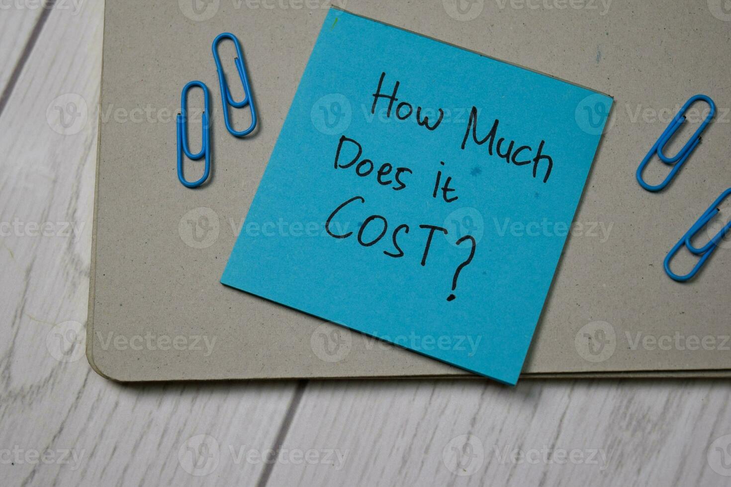 How Much Does it Cost write on sticky note isolated on wooden table. photo