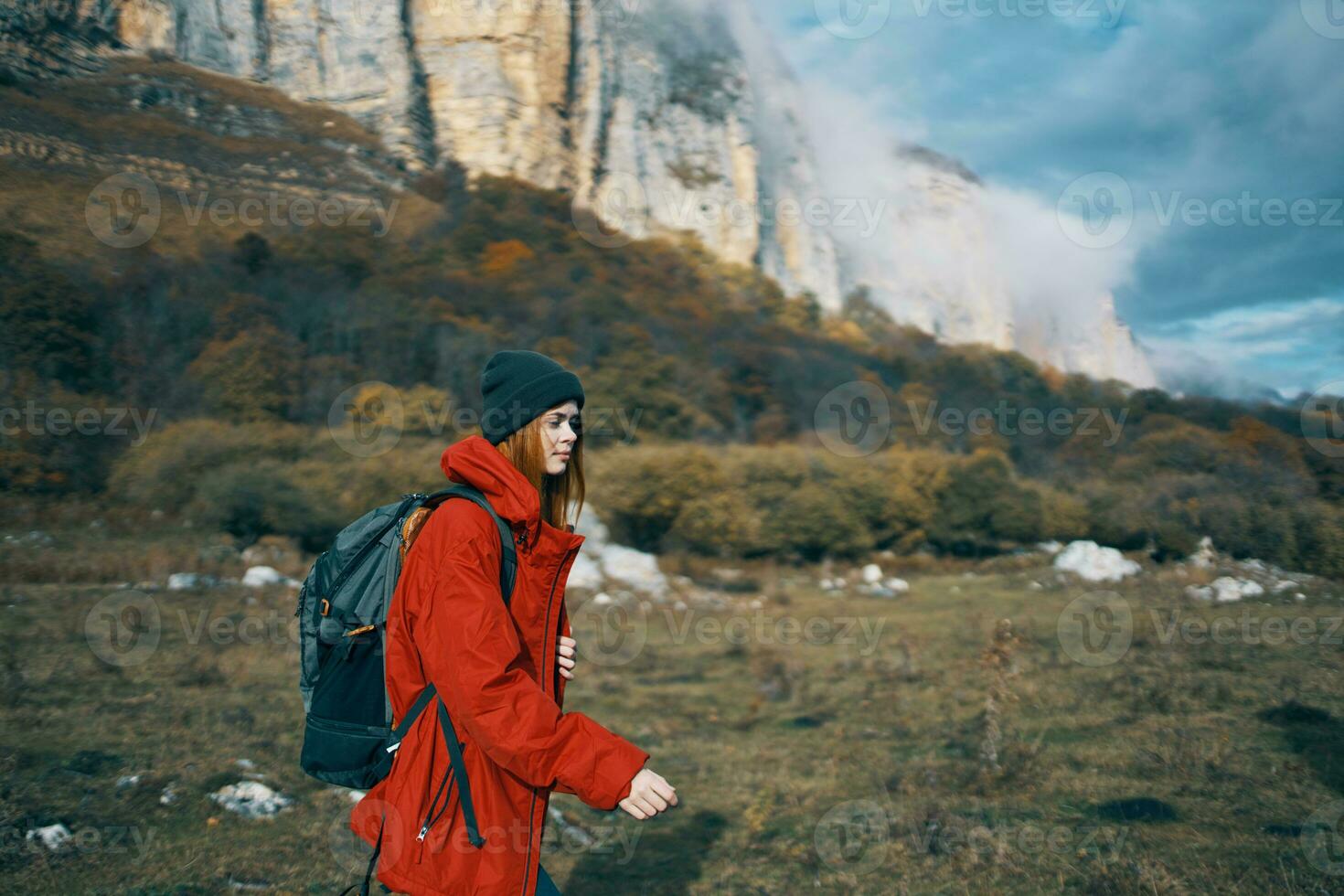 woman in jackets caps with a backpack on her back walks in the fall in the mountains and in nature photo