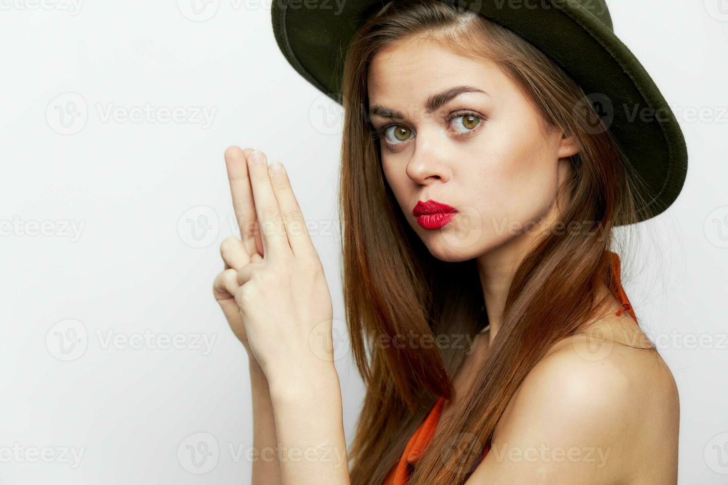 Woman with a hat Side view of fingers in the form of pistols on her head photo