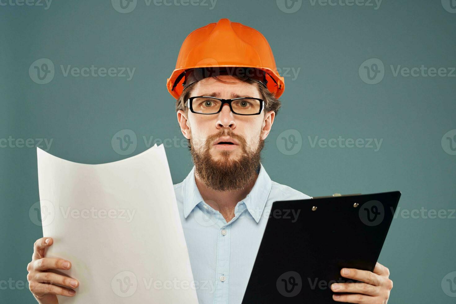 A male engineer in an orange hard hat with documents in the hands of construction drawings photo