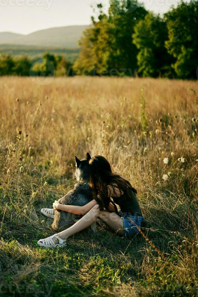 mujer sentado en un campo con un perro tejonero perro sonriente mientras gasto hora en naturaleza con un amigo perro en otoño a puesta de sol foto