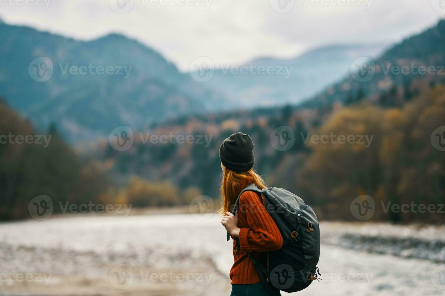 woman in a hat with a backpack are resting in the mountains in nature near the river photo