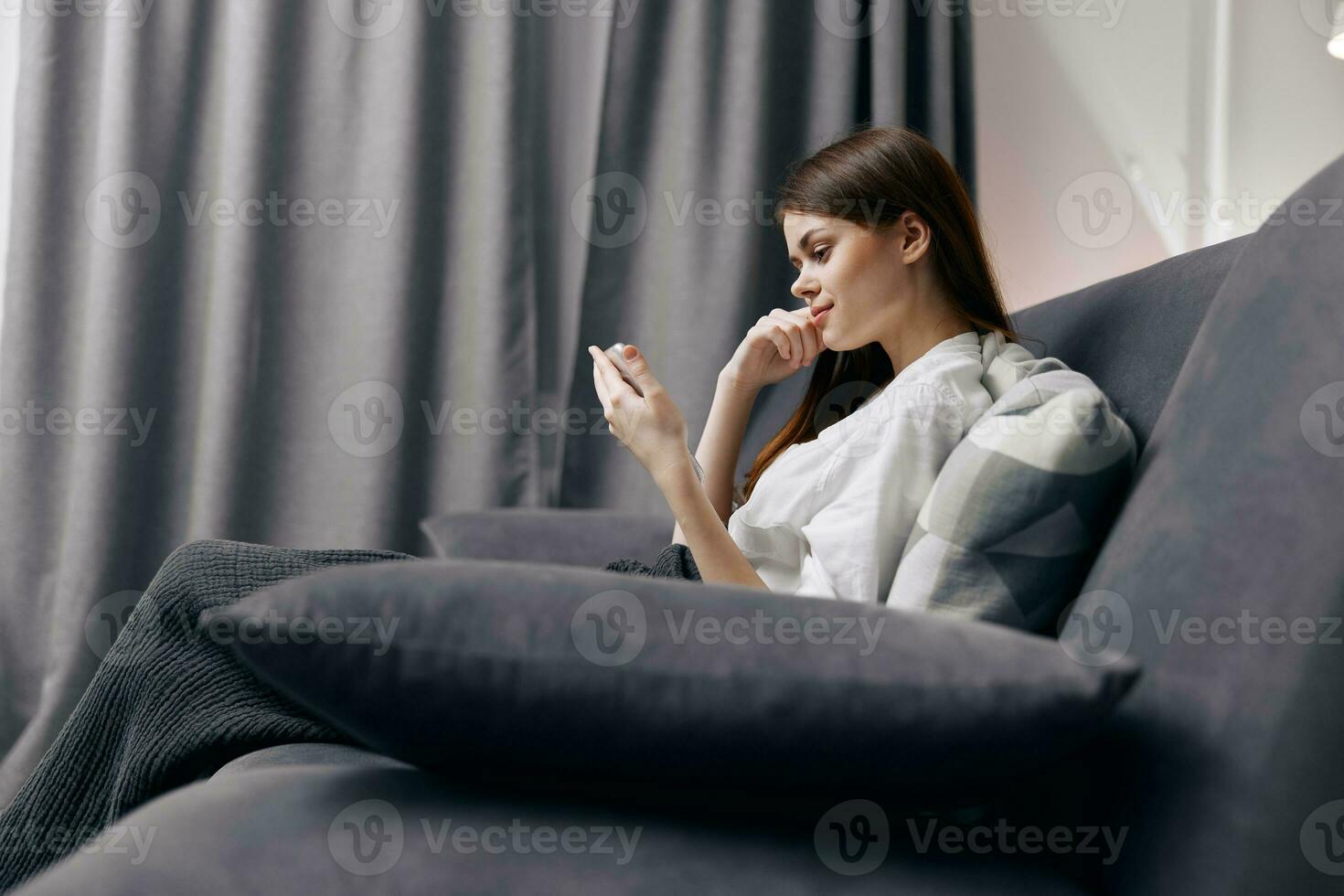 woman on sofa with phone in hand side view photo