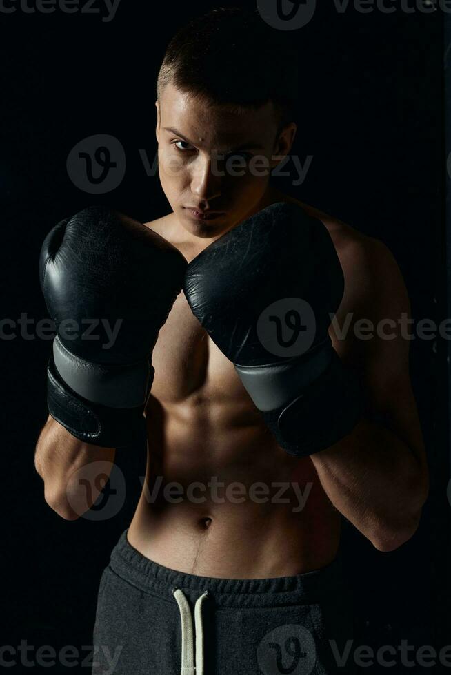 boxer in black gloves on a dark background inflated torso bodybuilder fitness photo