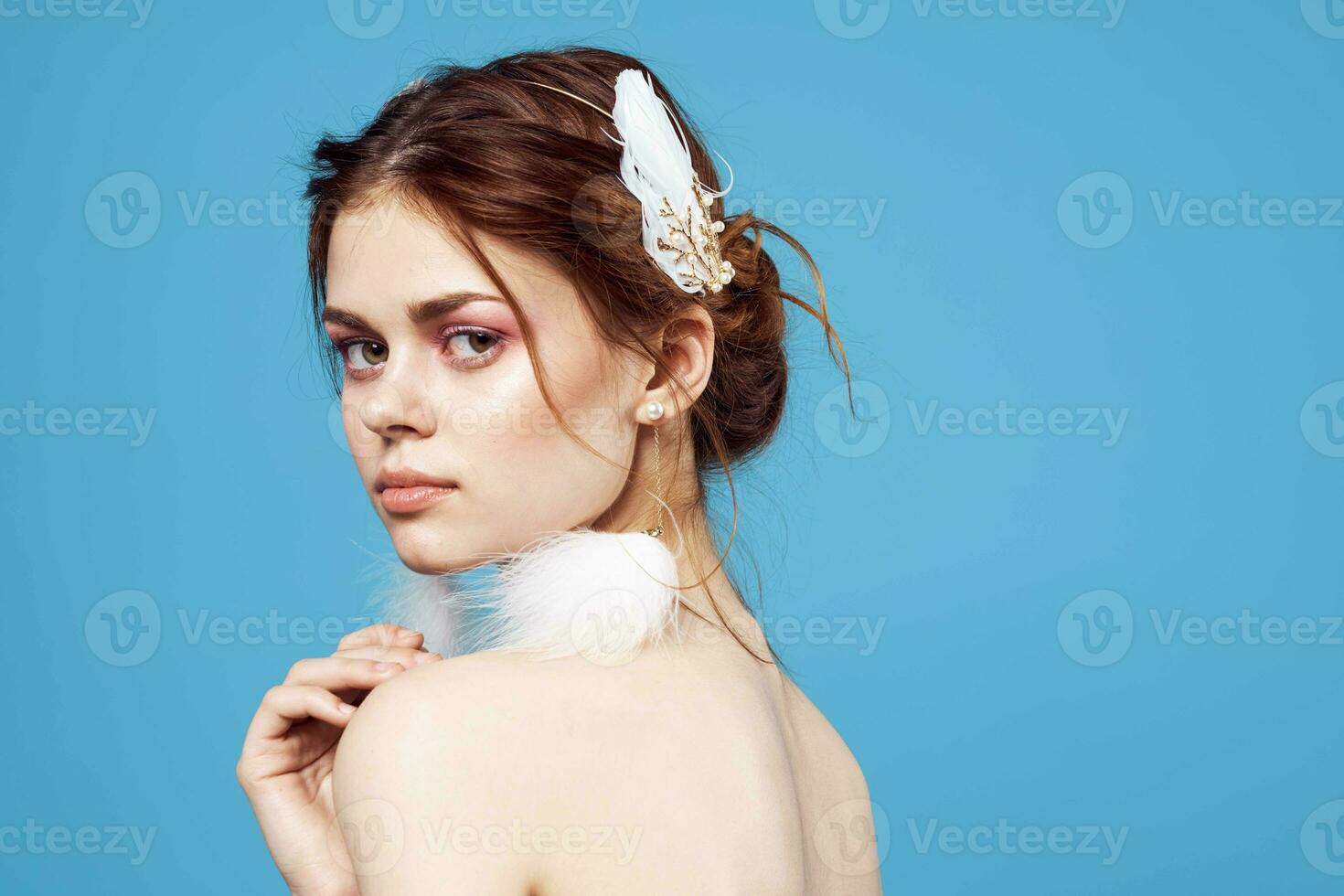 glamorous woman with fluffy earrings bright makeup clear skin blue background photo
