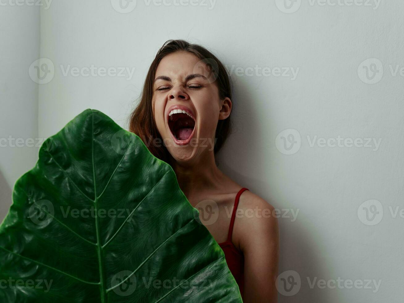 emotional woman with wide open mouth green palm leaf studio photo