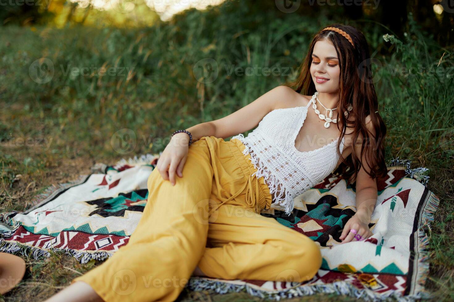 joven hermosa hippie mujer acostado en el suelo en naturaleza en el otoño en eco ropa en amarillo pantalones en el puesta de sol ligero foto