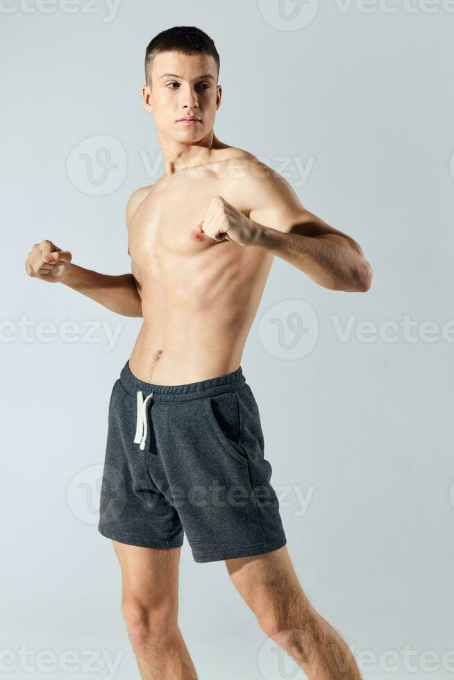 athlete in shorts gestures with his hands on a gray background and bodybuilders workout photo