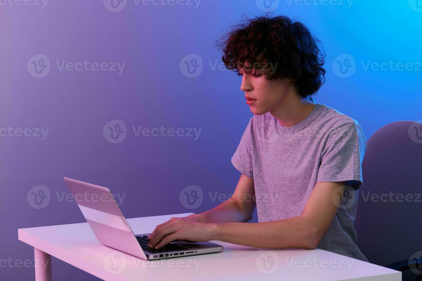 curly guy in front of laptop entertainment violet background photo