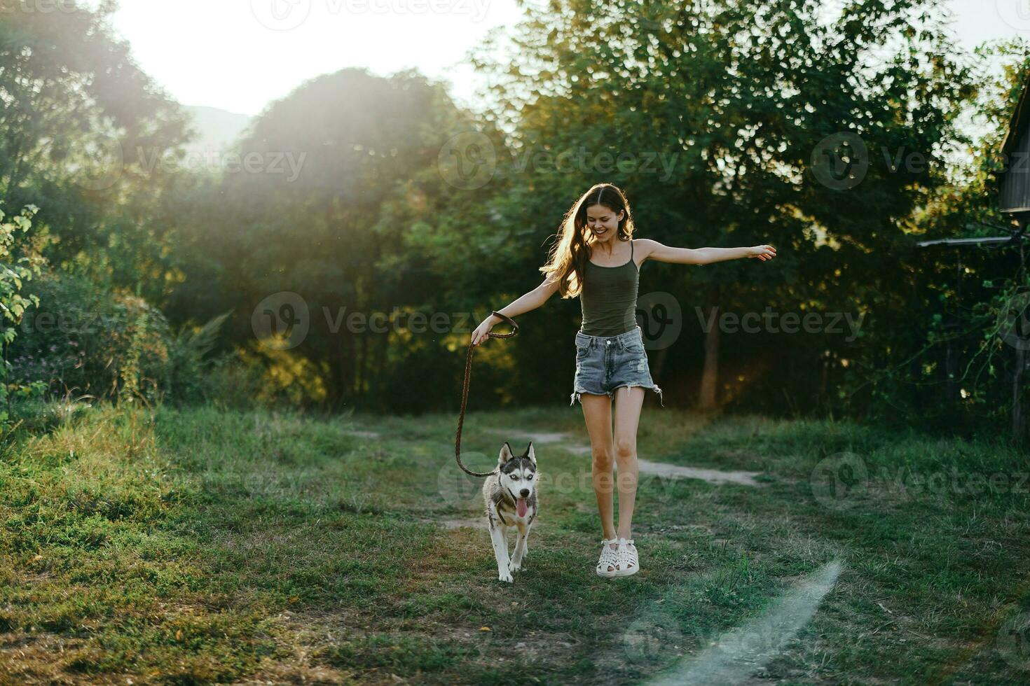 A woman runs with a dog in the forest during an evening walk in the forest at sunset in autumn. Lifestyle sports training with your beloved dog photo