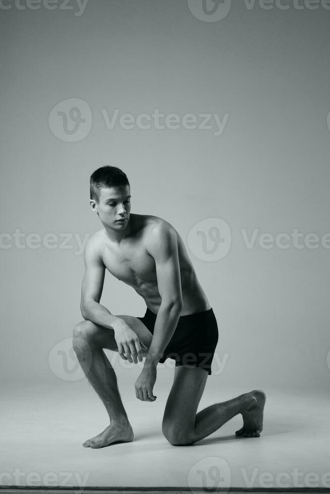 athlete kneeling indoors muscles biceps bodybuilder black and white photography photo