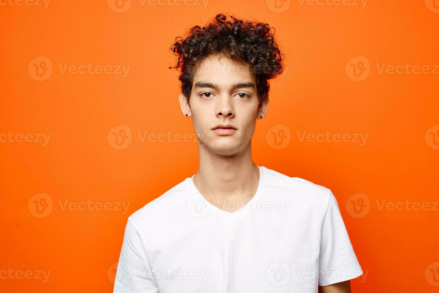 linda chico con Rizado pelo en un blanco camiseta de cerca foto