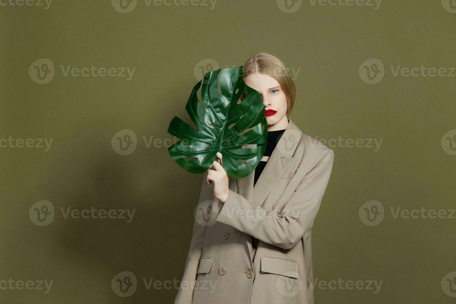 blonde woman green palm leaf coat bright makeup studio model unaltered photo