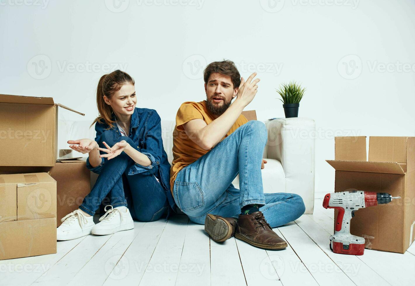 A man and a woman are sitting on the floor with open boxes and tools for repair photo