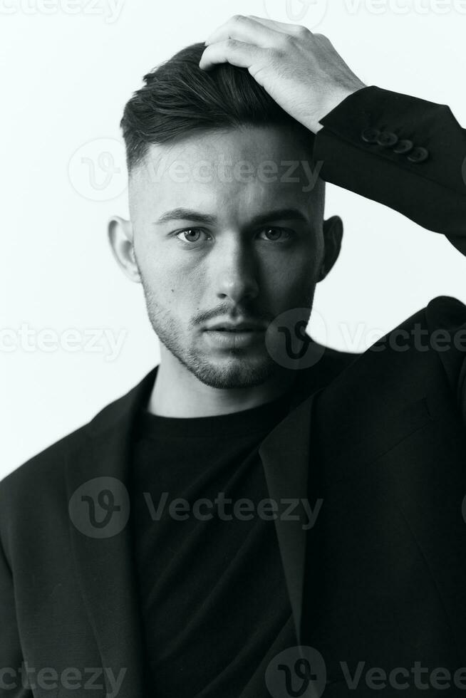 Modelling snapshots. Closeup portrait of self-confident attractive handsome muscular guy man in jacket looks at camera sitting on chair in white studio background. Black and White concept. Copy space photo