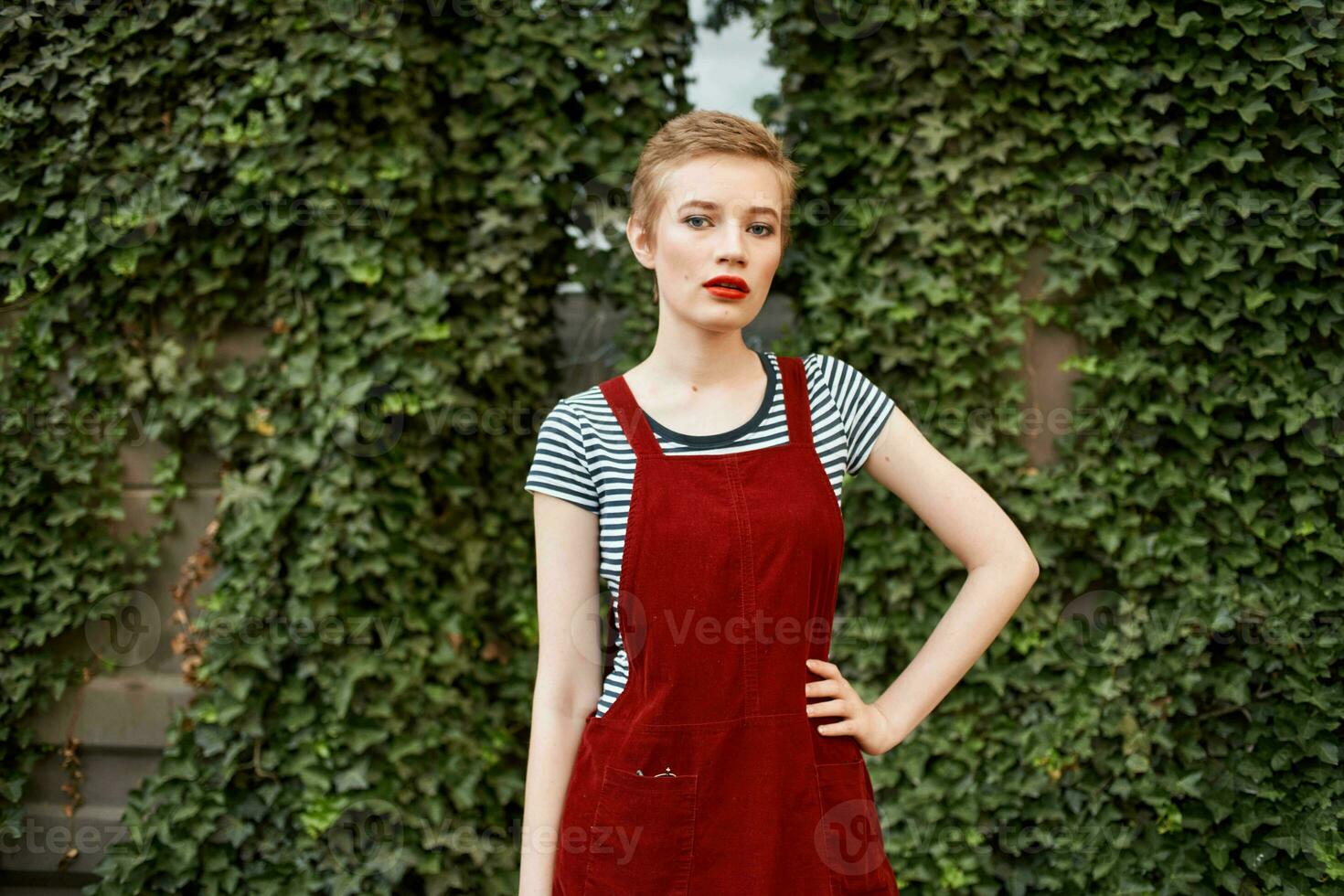 pretty woman with short hair outdoors on a background of bushes photo