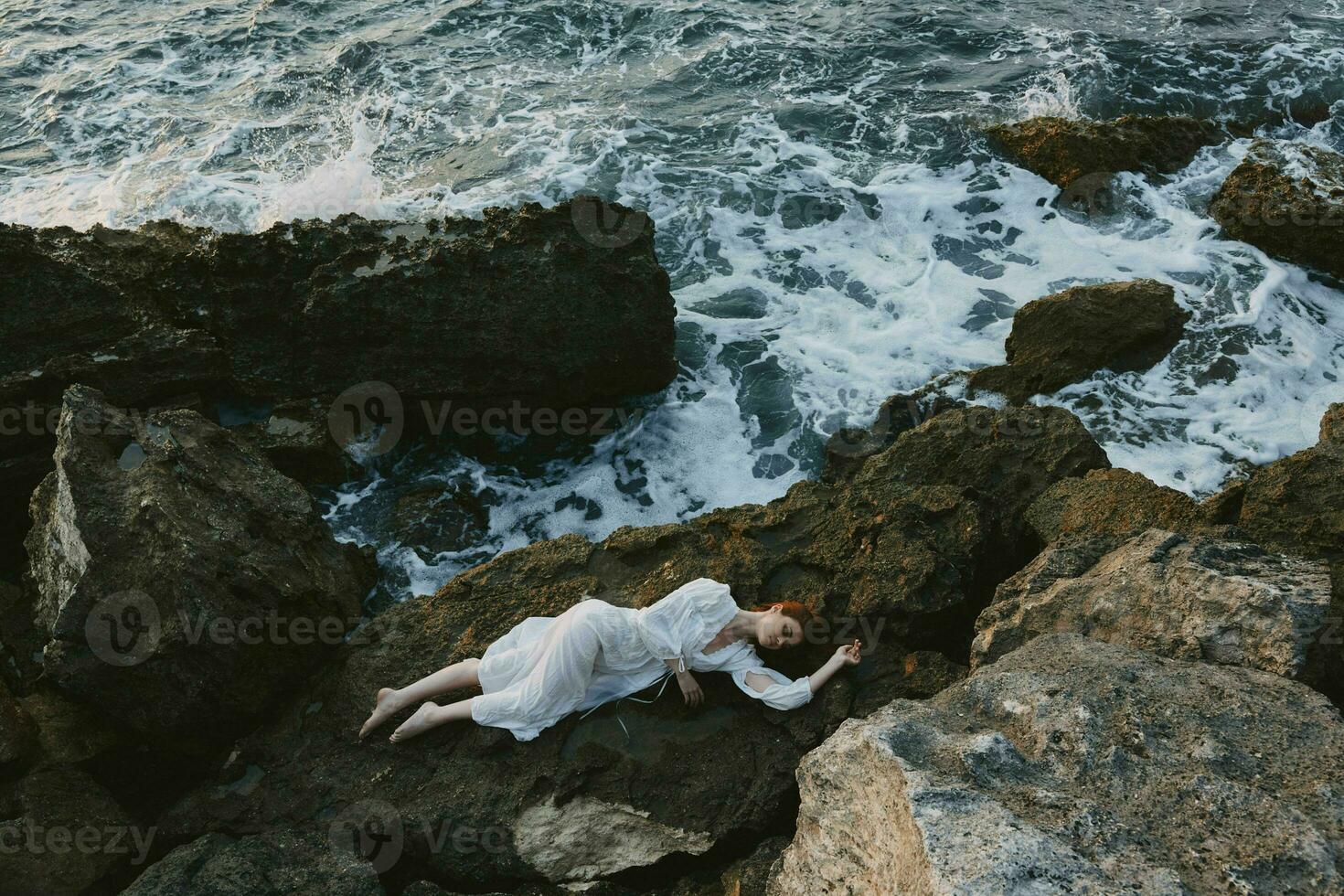 hermosa novia acostado en rocoso costa con grietas en rocoso superficie vacaciones concepto foto