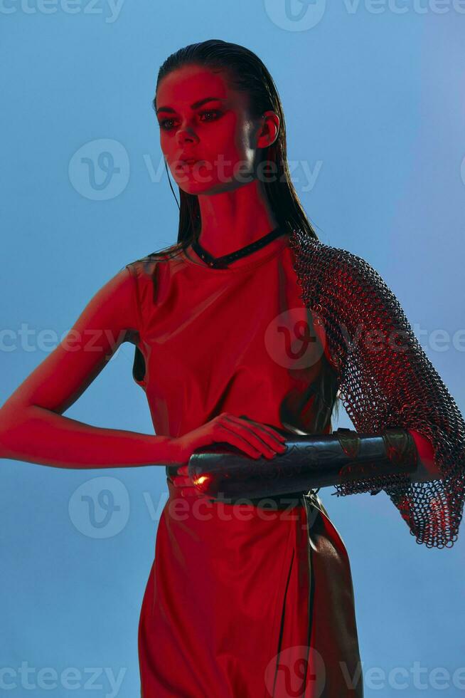 young woman in dress arm in armor chain mail protection blue background photo