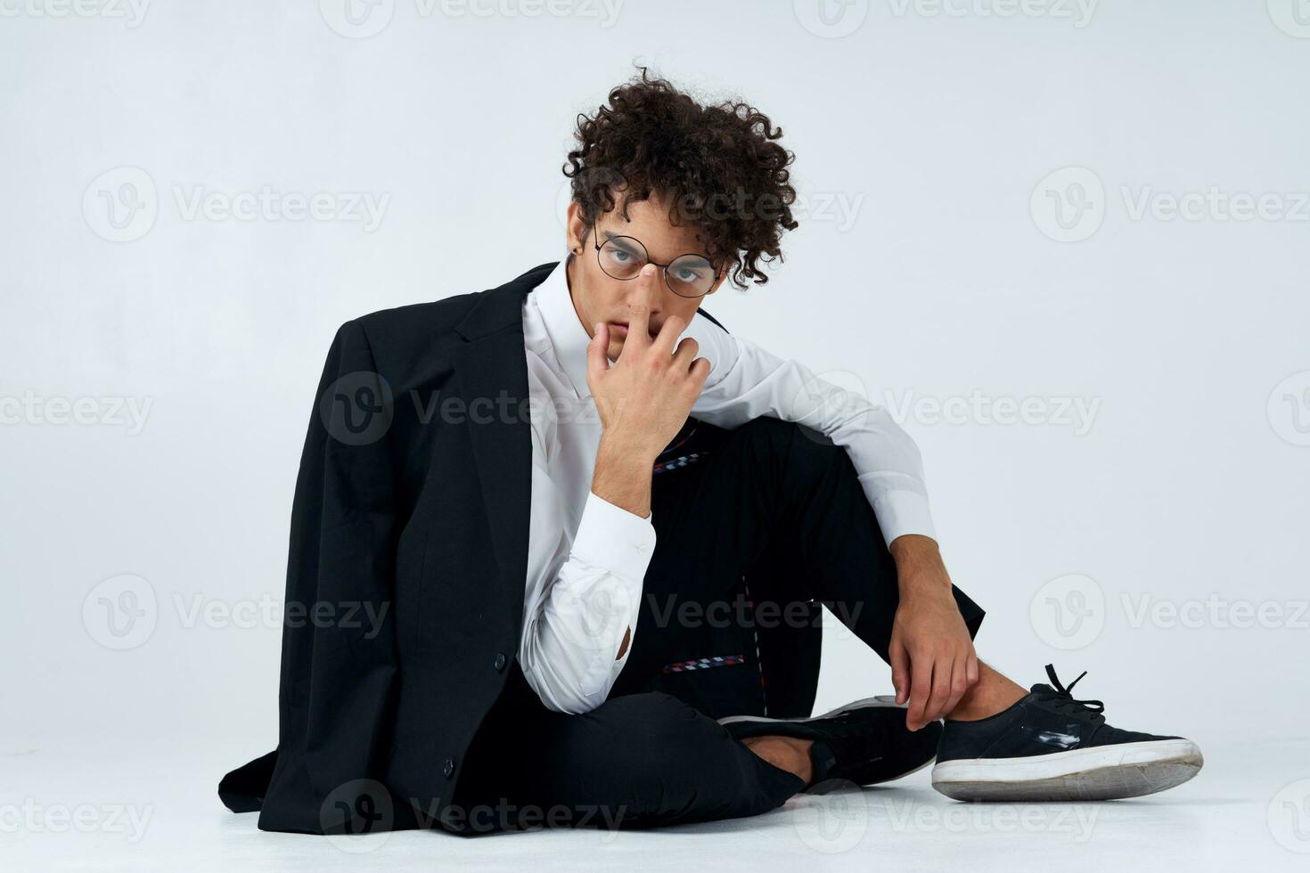 fashionable guy in classic suit and glasses sitting on the floor in a bright room cropped view photo