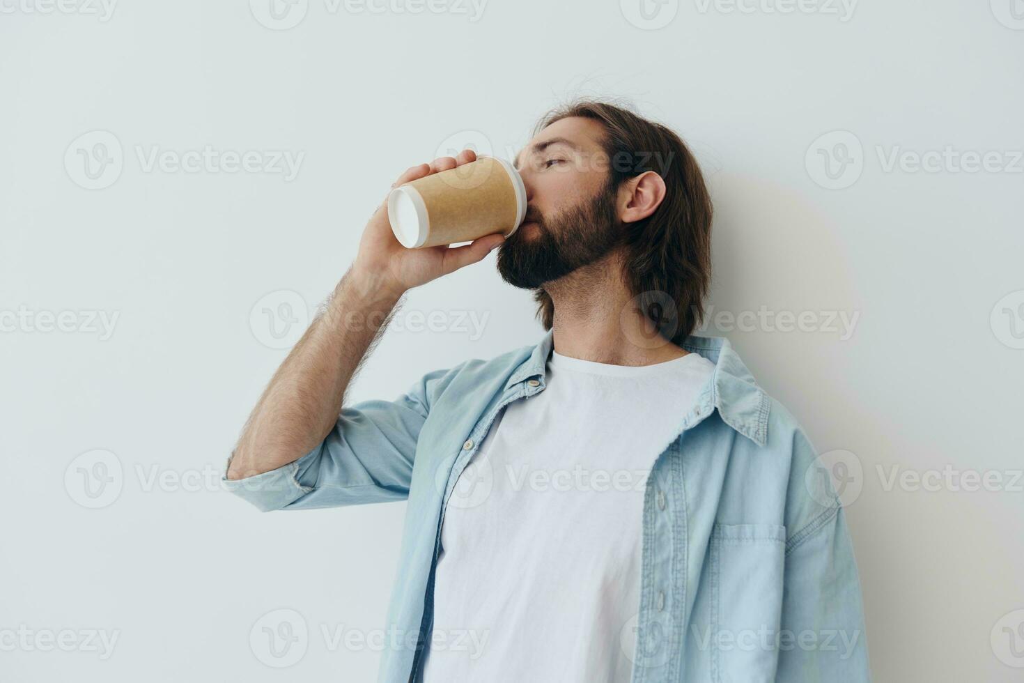 Freelance Millennial man with beard drinking coffee from a crab cup in stylish hipster clothes on a white background photo