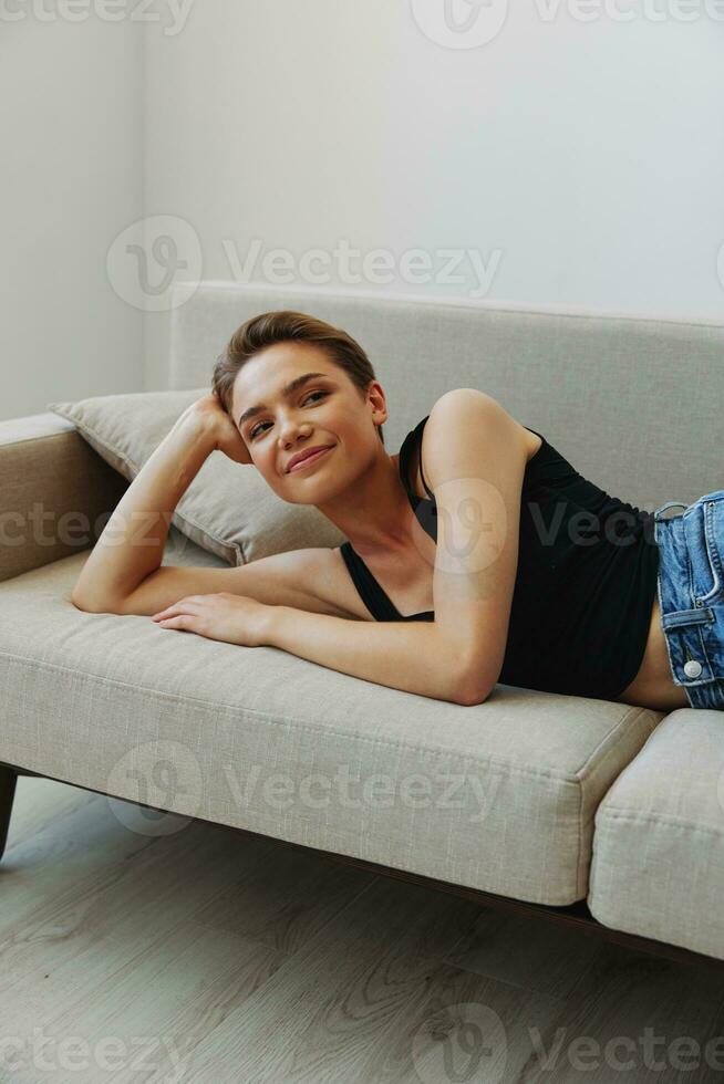 Young woman with short haircut hair having fun at home on the couch smile and happiness, vacation at home, natural posing without filters, free copy space photo