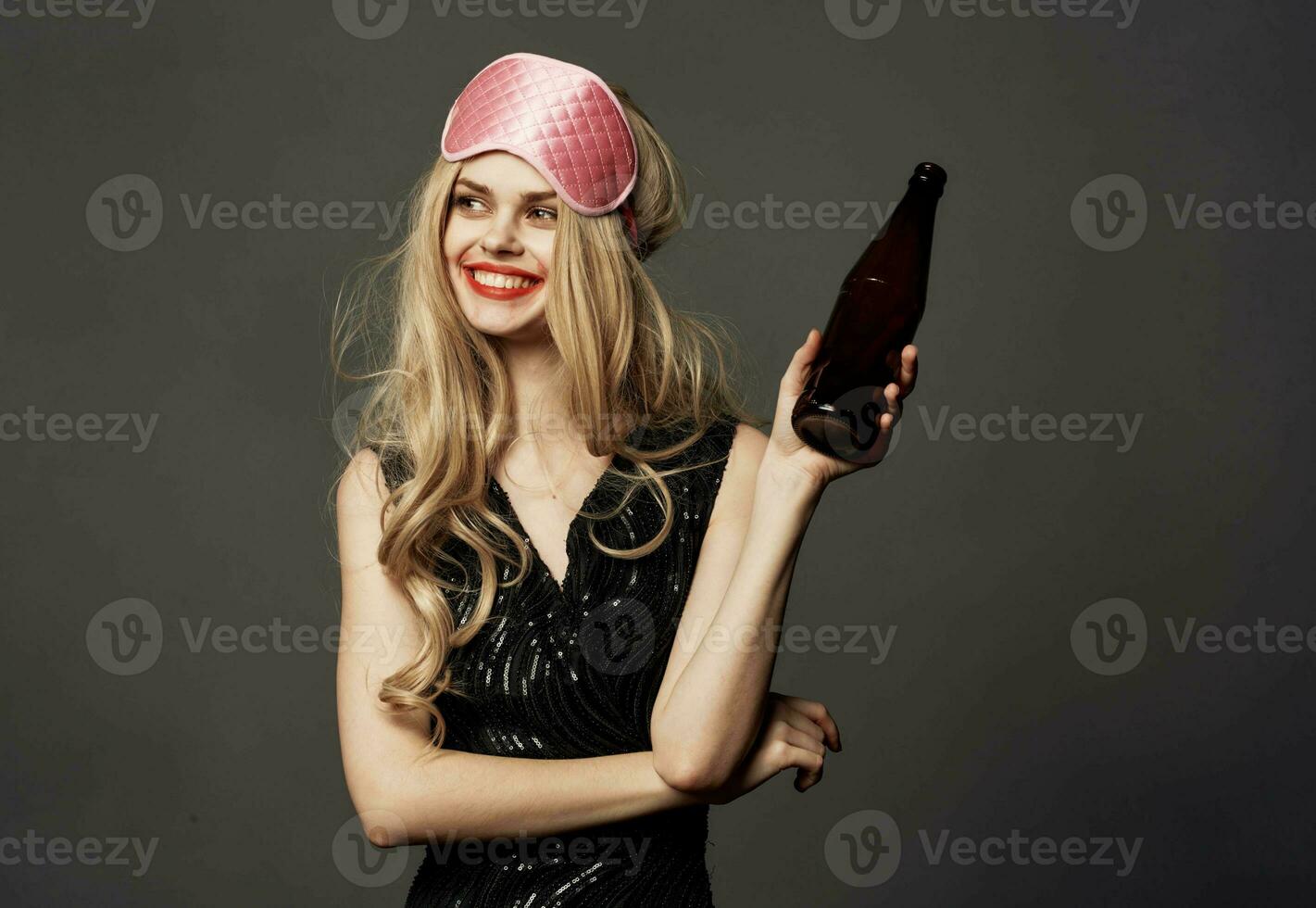 Beautiful blonde with a pink sleep mask and a bottle of beer in her hand photo