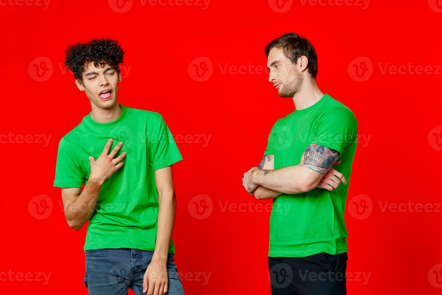 two men in green t-shirts are standing side by side communication isolated background photo