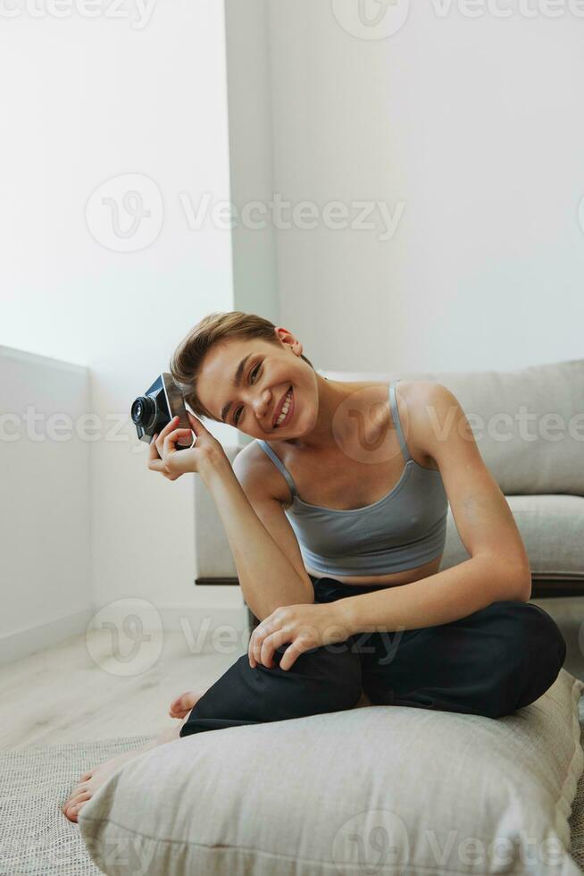 Happy smile woman holding an old camera and taking pictures of herself as a weekend photographer in home clothes with a short haircut hair without filters on a white background, free copy space photo