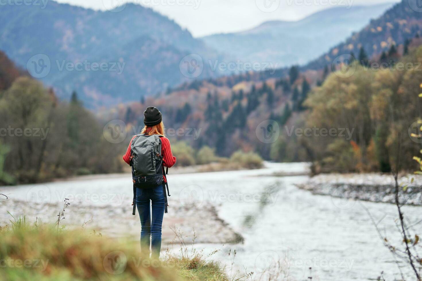 woman in a red sweater with a backpack in the mountains on nature near the river pond lake photo
