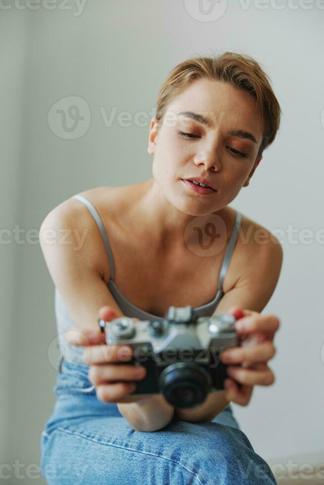 mujer fotógrafo disparo en estudio en antiguo película cámara a hogar en sofá retrato, blanco fondo, gratis Copiar espacio, Lanza libre fotógrafo foto