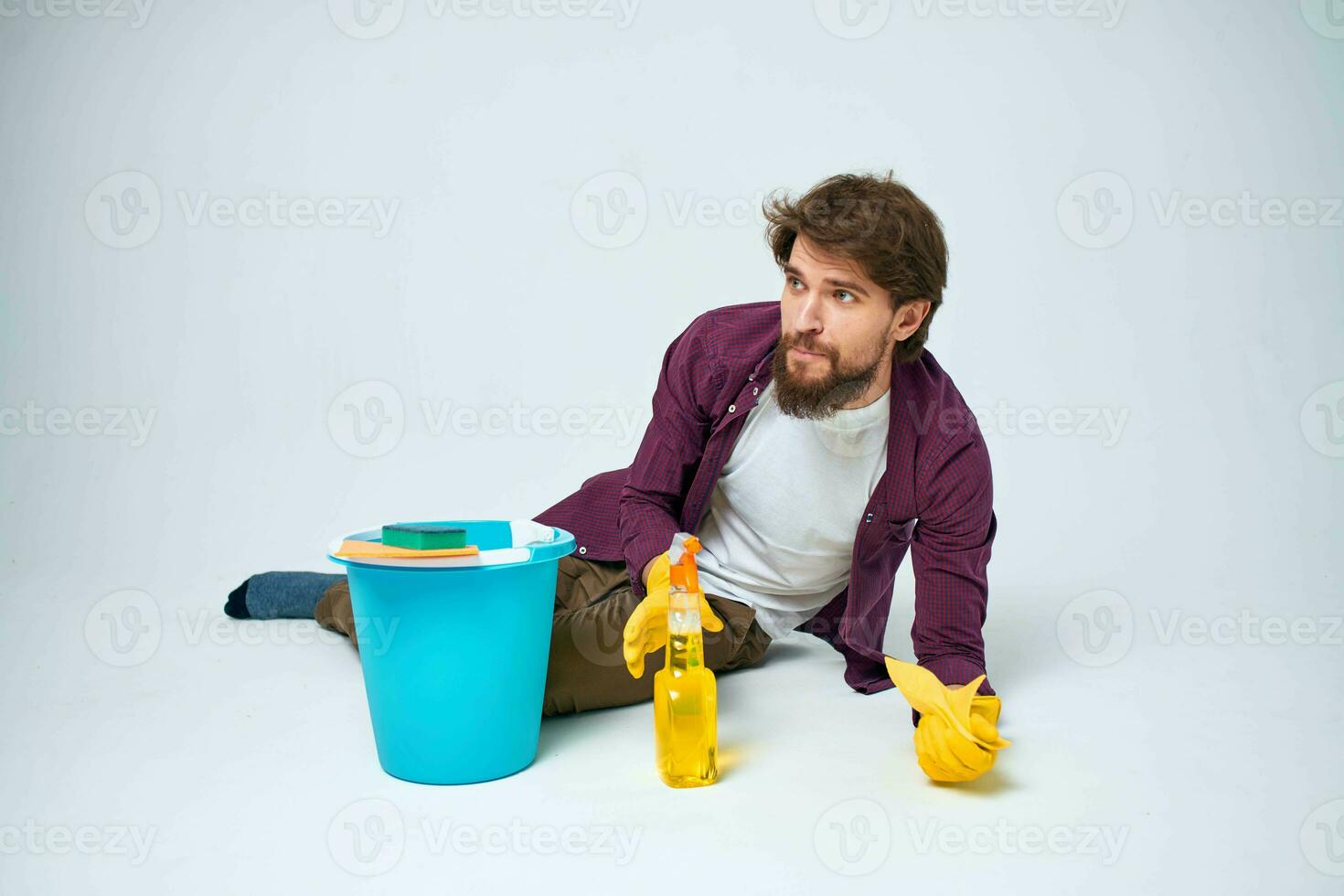 A man lies on the floor with a bucket of detergent cleaning service light background photo