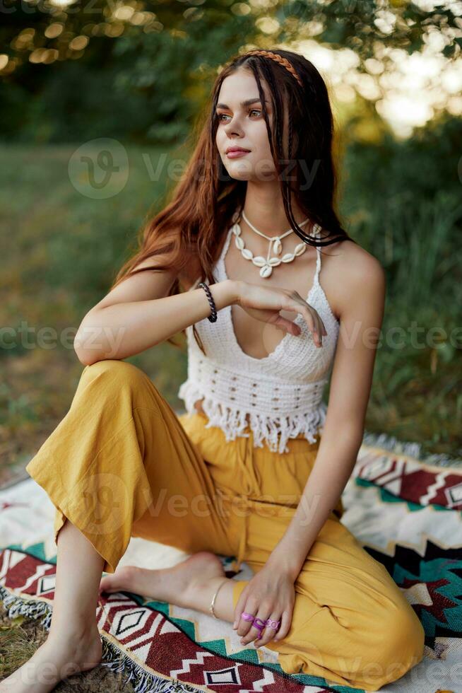 joven hermosa hippie mujer sentado en el suelo en naturaleza en el otoño en eco ropa en el puesta de sol luz, un estilo de vida de viaje y armonía con el mundo foto