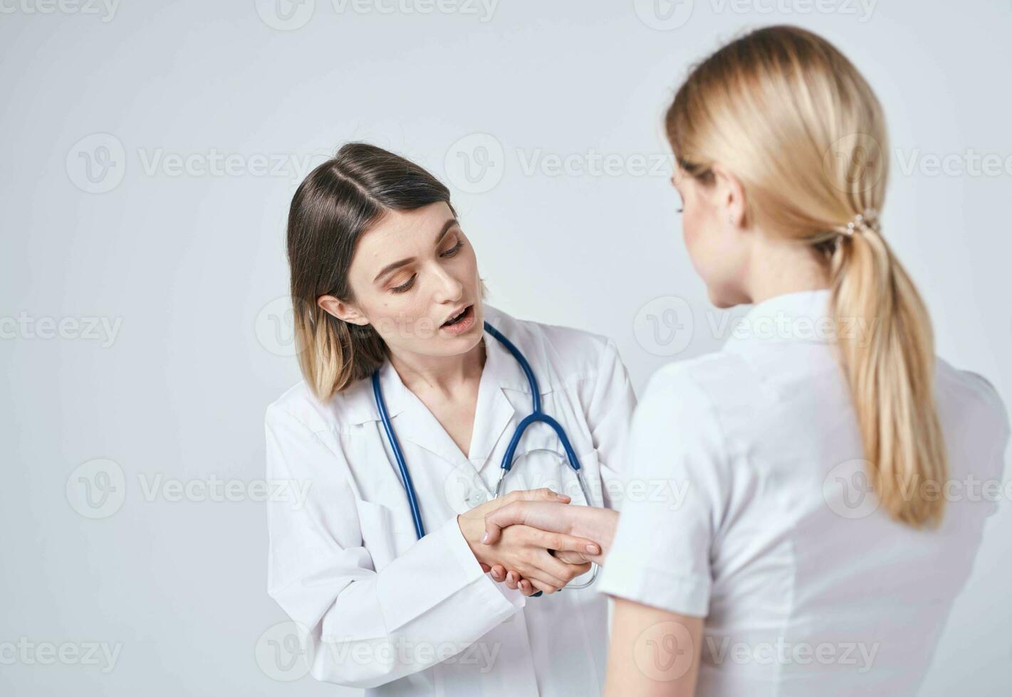 Happy woman doctor in medical gown with stethoscope and patient back view photo