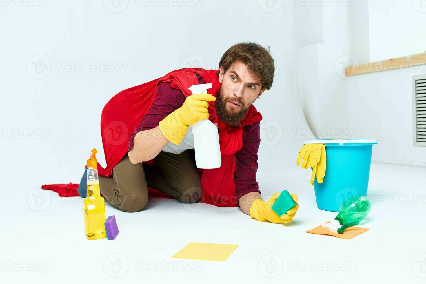 A man with cleaning supplies in a red raincoat on the floor of a home interior professional photo