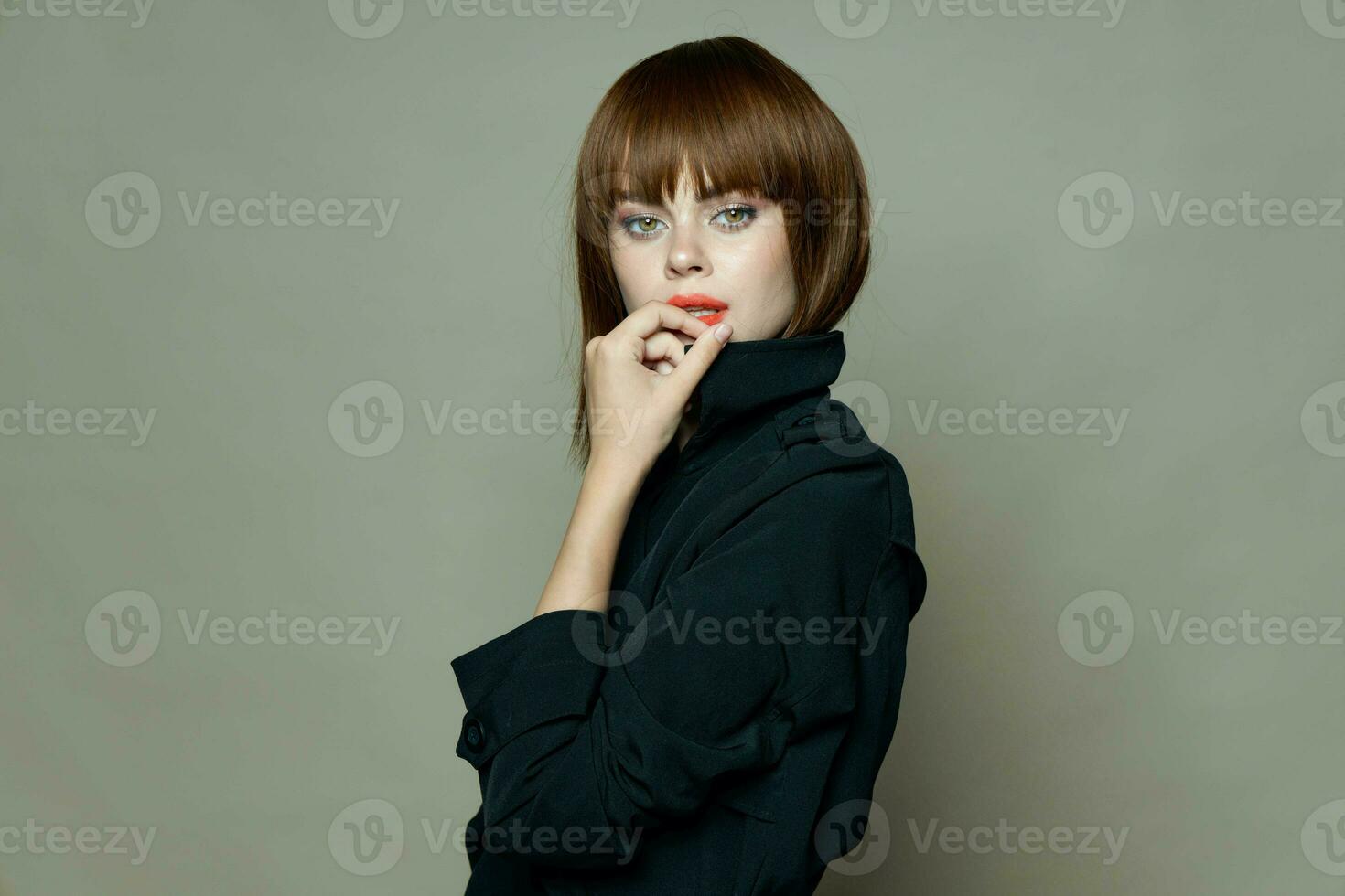 Charming woman in a black coat looks at the camera photo