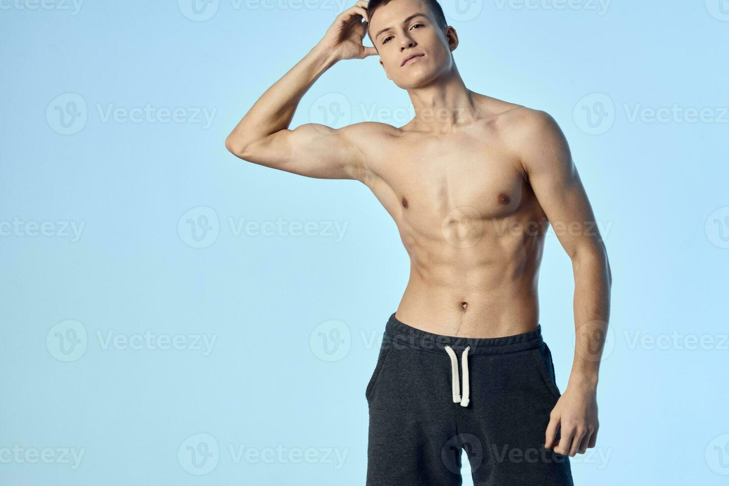 sporty man holding hand on head with pumped up body workout blue background photo