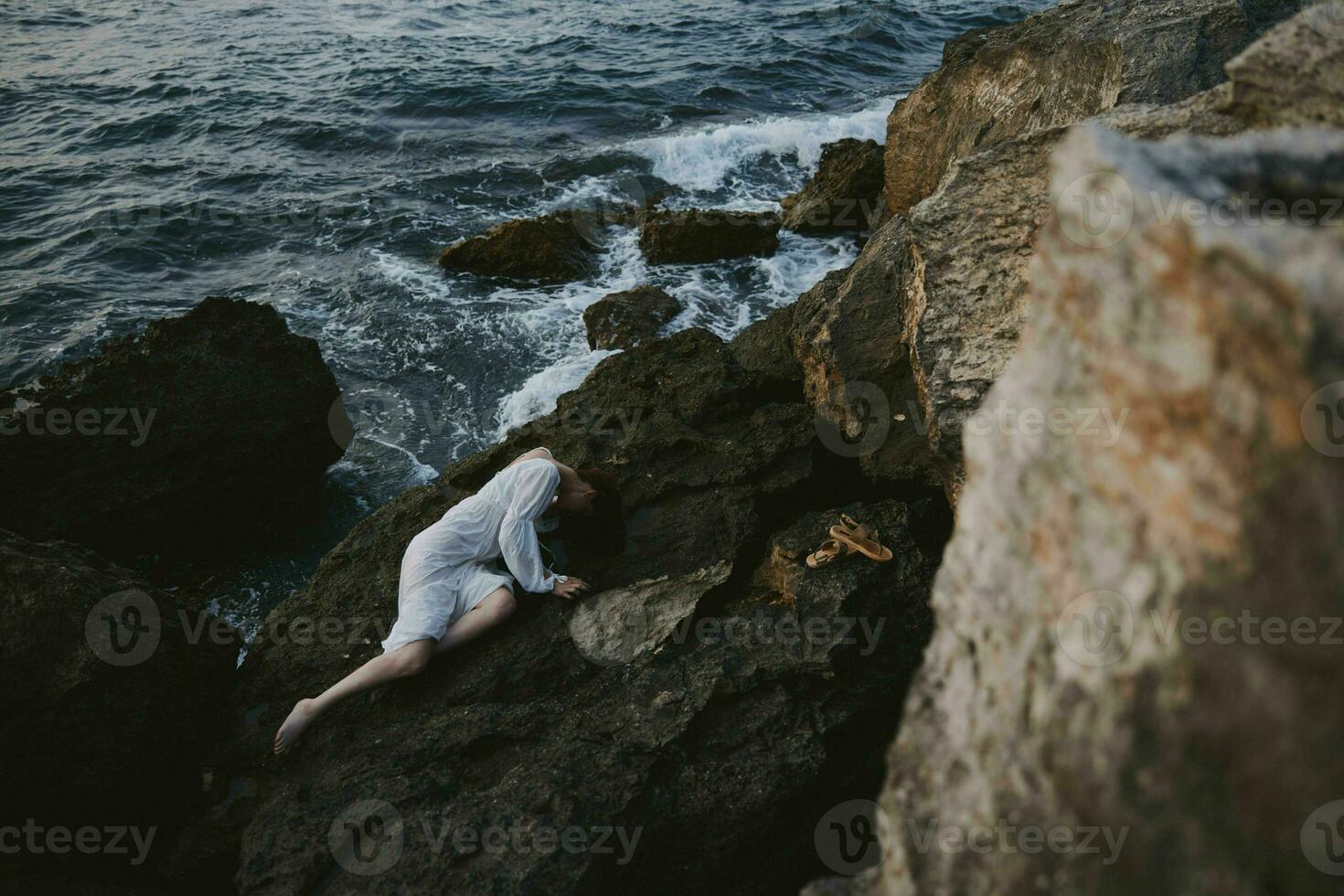 sensual woman in a white dress lying on a stone in a white dress landscape photo