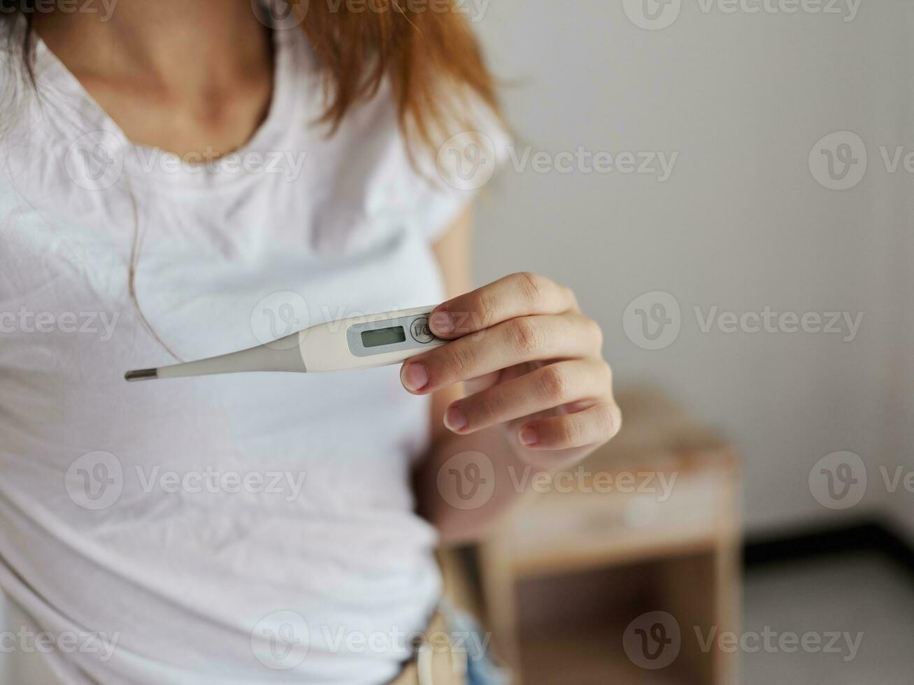 woman in white t-shirt holding thermometer temperature check photo