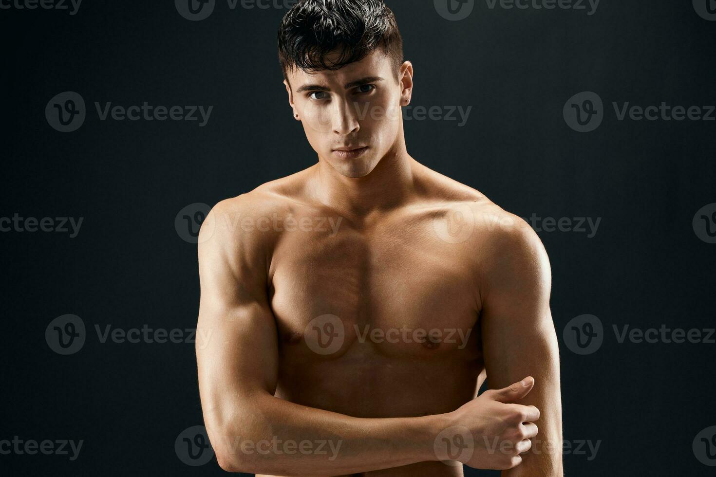 male bodybuilder with a pumped-up body posing against a dark background photo
