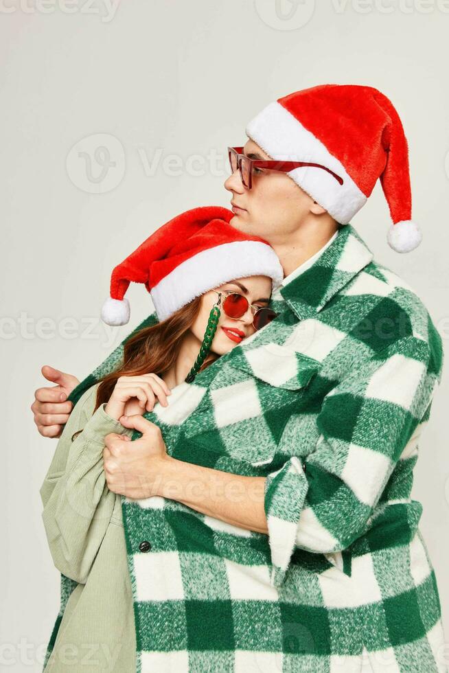 young couple wearing sunglasses christmas hats hugs care holiday photo